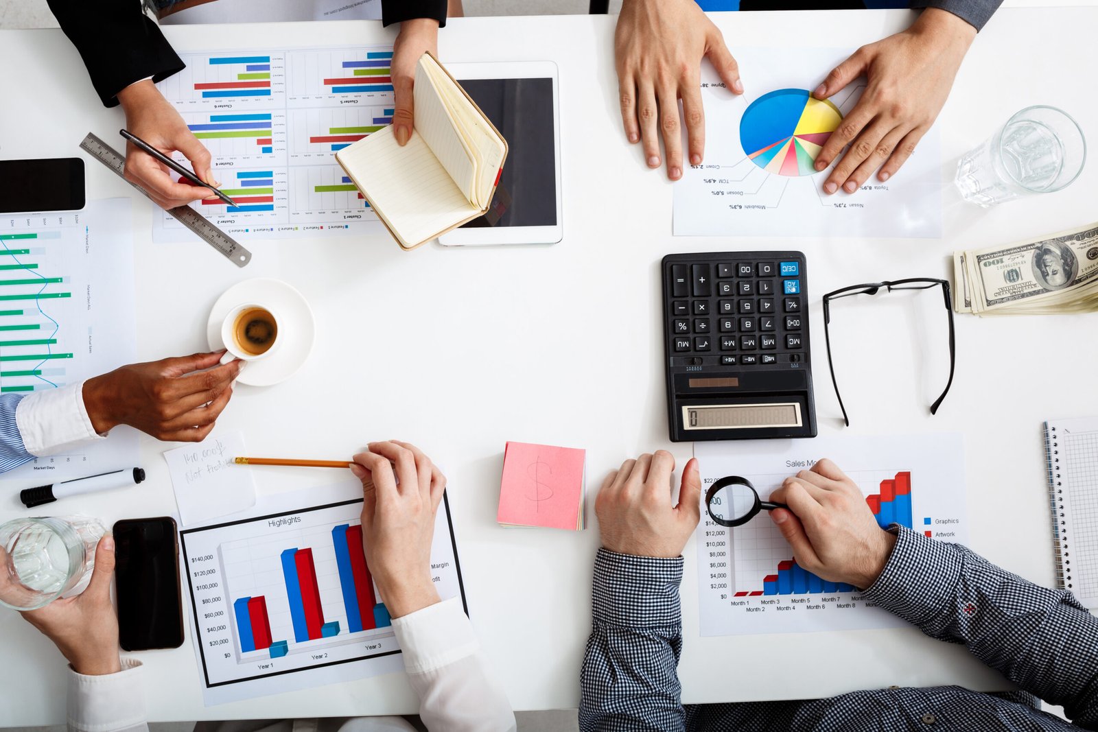 Picture of businessmen's hands on white table with documents, coffee and drafts